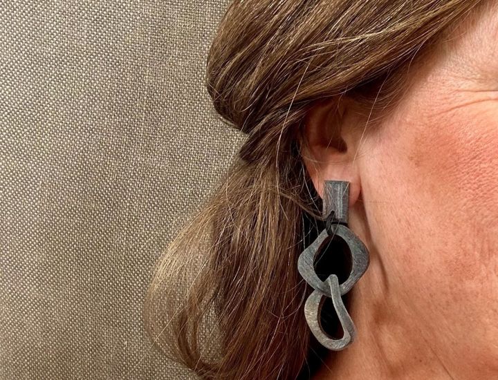 Geborstelde buffelhoorn schakeloorbellen met een twist. 7 x 3 cm. Facetgeslepen stud