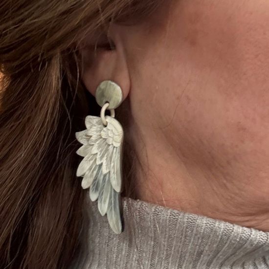 Lasergesneden buffelhoorn wings oorbellen, in lichte tintjes, mat. Totale lengte 7.5 cm.