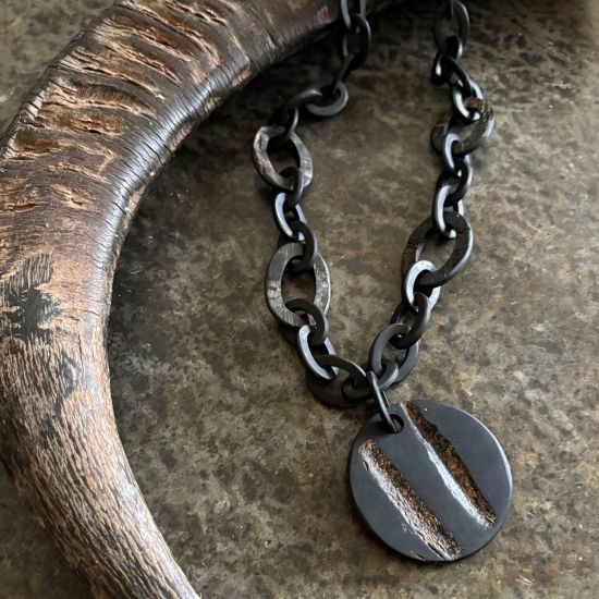 Handgemaakt buffelhoorn collier met Ø6cm hanger, in een matte & ruwe finish. Lengte 80 cm.